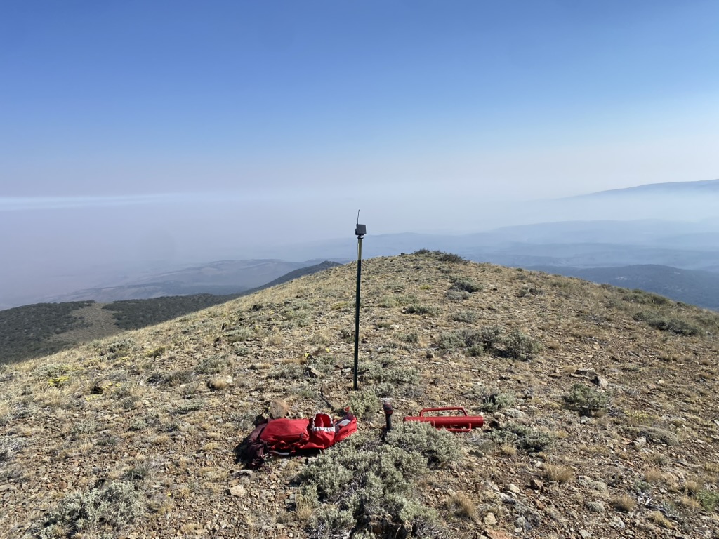 T-post mesh mount on a rocky Fox Mountain ridge overlooking smoke-filled desert valleys below