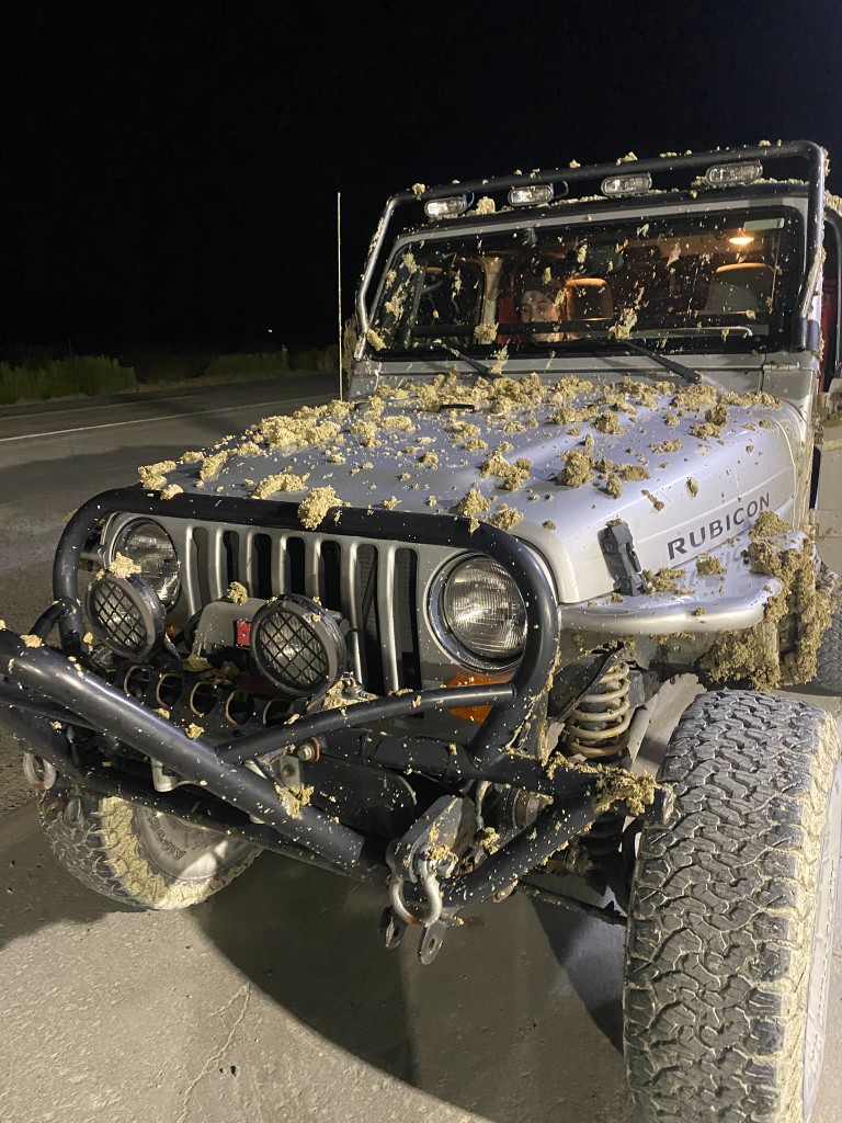 Silver Jeep Rubicon caked in playa mud at night after bogging out near Gerlach