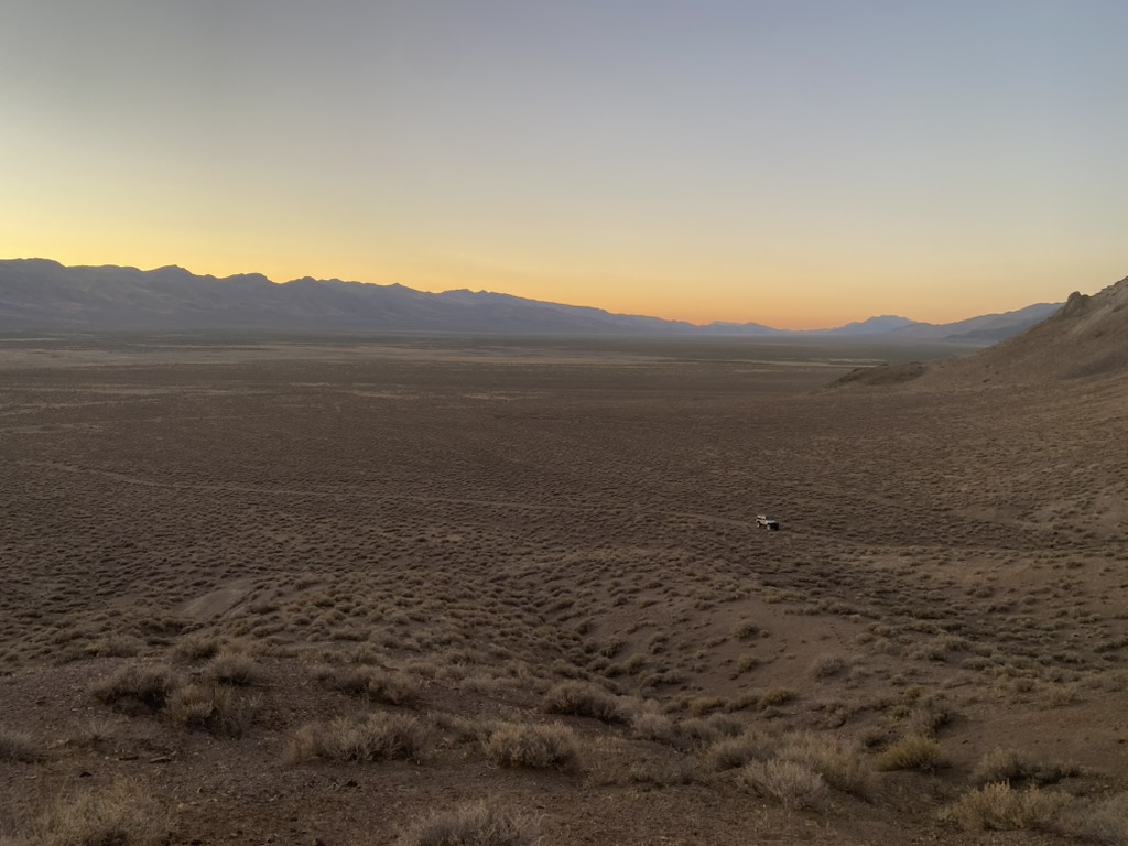 Desert valley at dusk with a distant jeep on a dirt track below Russell Peak